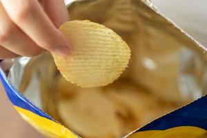 hand halten kartoffelchips mit snackbeutel foto