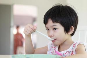 kleines asiatisches mädchen, das frühstückt foto