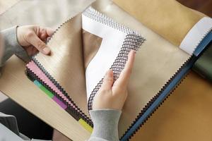Designerin mit Stofffarbmustern, die Textilien für Vorhänge auswählen foto