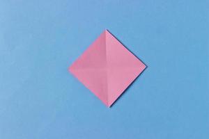 Schritt 2. Origami-Schweinskopf. Wir falten gegenüberliegende Ecken zueinander, sodass wir zwei diagonale Faltlinien erhalten. foto