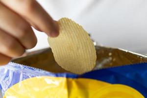 hand halten kartoffelchips mit snackbeutel foto