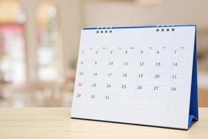 Tischkalender aus weißem Papier auf Holztisch mit verschwommenem Bokeh-Hintergrund, Termin- und Geschäftstreffenkonzept foto