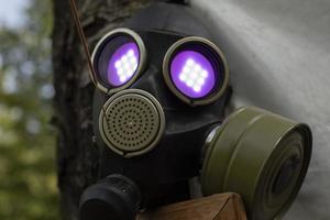 Gasmaske mit Flamme in den Augen. violettes Licht aus den Augenhöhlen. Rauchschutz. foto
