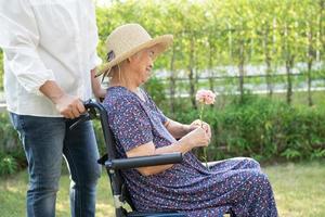 pflegekraft hilfe und pflege asiatische seniorin oder ältere alte dame patientin sitzend und glücklich im rollstuhl im park, gesundes starkes medizinisches konzept. foto