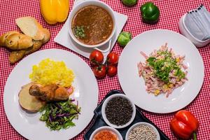 eine Nahaufnahme von oben auf den Serviertisch zum Mittagessen, Reis und gebratenes Hühnergericht, Suppe, Salat, Gewürze foto