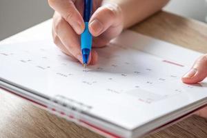 Frauenhand mit Stift schreiben auf Kalenderdatum Geschäftsplanungstermin Besprechungskonzept foto