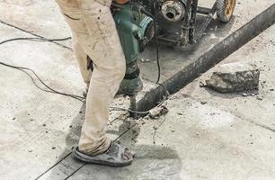 bauarbeiter, der bohrhammer verwendet, der betonoberfläche bohrt foto