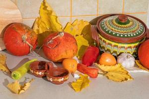 Saisonale Ernte von Kürbissen und Gemüse, Zutaten für die Zubereitung eines Gerichts, Werbung und Herbstkonzept - Nahaufnahme von Kürbissen und Blättern auf dem Tisch zu Hause foto