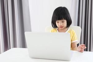 kleine asiatische studentin lernt online mit laptop-computer zu hause foto