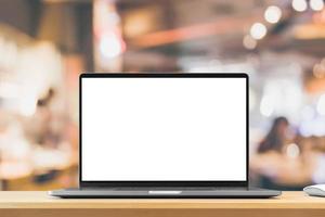 Laptop mit leerem Bildschirm auf Holztisch mit Café-Coffeeshop-Unschärfehintergrund foto