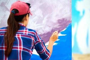 Künstlerin malt auf Holzleinwand, malt abstraktes buntes Bild, Festival im Freien foto