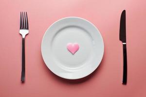 Warten auf ein Lieblingsgericht im Restaurant oder Café. Herz auf Teller mit Gabel und Messer. Verliebte treffen sich bei einem täglichen Mittagessen. foto