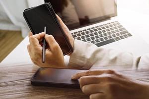 Geschäftsfrau arbeitet mit Laptop-Computer, Tablet und Smartphone im modernen Büro mit virtuellem Symboldiagramm im Modernoffice im Morgenlicht foto