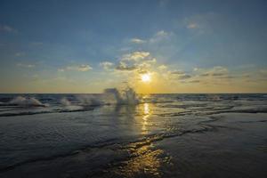 Schöne Aussicht auf das Meer mit der Sonne, die in einem blauen Himmel im Hintergrund scheint foto