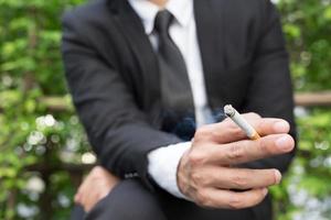 Geschäftsleute Zigaretten zum Rauchen sitzen im Park in der Raucherzone. foto