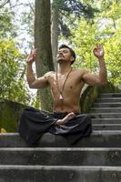 Junger Mann, der auf einer Treppe in einem Wald, Mexiko, meditiert