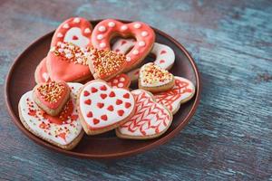 verzierte herzförmige Plätzchen in der Platte auf dem grauen Hintergrund. valentinstag-food-konzept foto