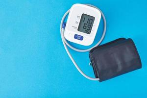 Digitales Blutdruckmessgerät auf blauem Hintergrund, Nahaufnahme. Gesundheitsversorgung und medizinisches Konzept foto