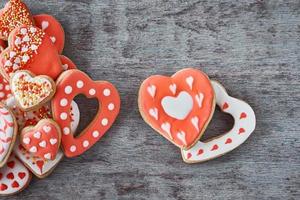 Zwei herzförmige Kekse und viele dekorierte Kekse auf dem grauen Hintergrund. Valentinstag-Konzept foto