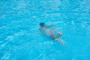 Junge in Tauchermaske schwimmt unter Wasser im Schwimmbad foto