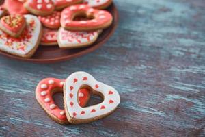 Zwei herzförmige Kekse und viele dekorierte Kekse auf dem grauen Hintergrund. Valentinstag-Konzept foto