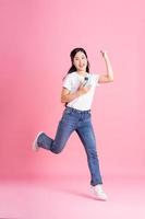 Ganzkörperbild eines asiatischen Mädchens, das auf rosa Hintergrund posiert foto