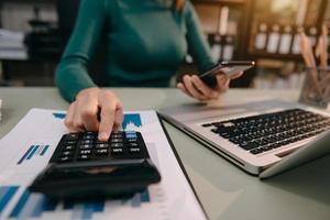 Geschäftsfrau, die am Schreibtisch arbeitet und einen Taschenrechner verwendet, um die Zahlen zu berechnen, Finanzbuchhaltungskonzept foto