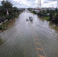 Überschwemmte Straßen, Menschen mit Autos, die durchfahren. Drohnenaufnahmen aus der Luft zeigen überschwemmte Straßen und vorbeifahrende Autos, die Wasser spritzen. foto