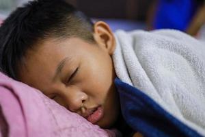 asiatischer junge schläft gut auf der matratze und decke in seinem schlafzimmer. schöne Träume foto