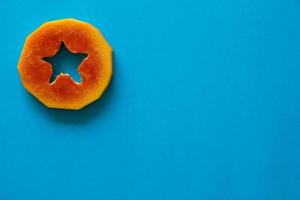 ein Stück orange Papaya auf blauem Hintergrund. foto