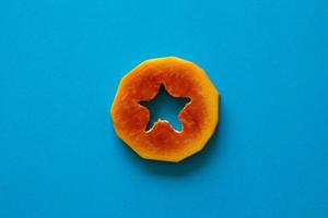 ein Stück orange Papaya auf blauem Hintergrund. foto