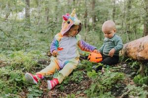 Zwei Kinder gehen mit einem Korb voller Halloween-Süßigkeiten im Wald spazieren foto