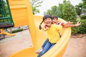 Süße kleine Mädchen Geschwister amüsieren sich an sonnigen Sommertagen auf dem Spielplatz im Freien. Kinder auf Plastikrutsche. lustige Aktivität für Kinder. aktive sportfreizeit für kinder foto