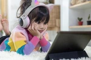 ein glückliches asiatisches kleines mädchen, das musik im wohnzimmer hört foto