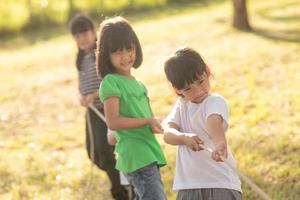 Kinder spielen Tauziehen im Park auf Sunsut foto