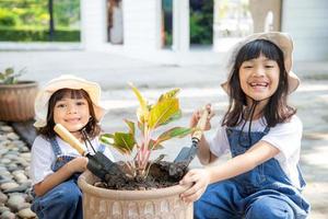 geschwister asiatisches mädchen pflanzt frühlingsblumen baum in töpfen im garten vor dem haus, kindererziehung der natur. für neues Leben sorgen. Feiertagskonzept zum Tag der Erde. Weltumwelttag. Ökologie. foto