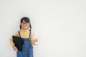 Asiatisches kleines Mädchen, das eine Abschlusskappe trägt und ein Diplom auf weißem Hintergrund hält foto