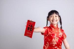 frohes chinesisches neujahr. lächelnde asiatische kleine mädchen, die roten umschlag halten foto