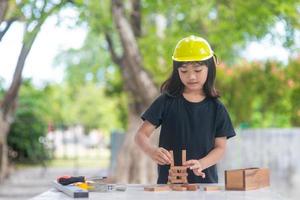 asiatische mädchenkinder, die als ingenieurhelm spielen, lächeln und sind am wochenende glücklich. foto