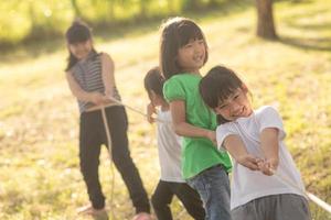Kinder spielen Tauziehen im Park auf Sunsut foto