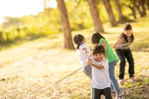 Kinder spielen Tauziehen im Park auf Sunsut foto