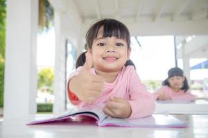 Kleines asiatisches Mädchen beim Unterricht im Klassenzimmer foto