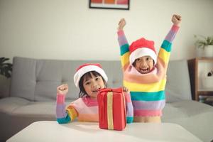 frohe weihnachten glückliche geschwistermädchen mit einem geschenk zu hause foto