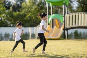 Zwei asiatische kleine Mädchen, die sich im Sommer auf einem Spielplatz im Freien amüsieren foto