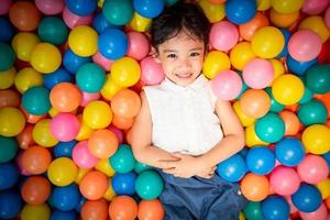 glückliches asiatisches mädchen, das in buntem kugelpool spielt foto