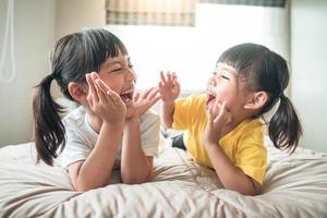 süße asiatische kinder, die auf dem bett liegen foto