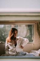 schöne junge Frau in einem weißen Hemd im Schlafzimmer zu Hause foto
