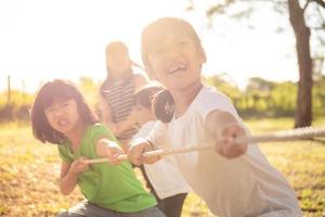 Kinder spielen Tauziehen im Park auf Sunsut foto