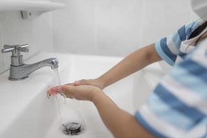 kleine asiatische mädchen waschen sich die hände im badezimmer. Weicher Fokus. Platz kopieren. foto