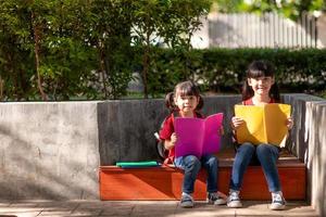 zwei schöne kleine Mädchen, die Bücher im Garten lesen. das Bildungskonzept foto